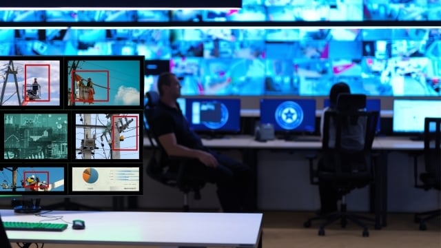 Security team watching security monitors along with AI