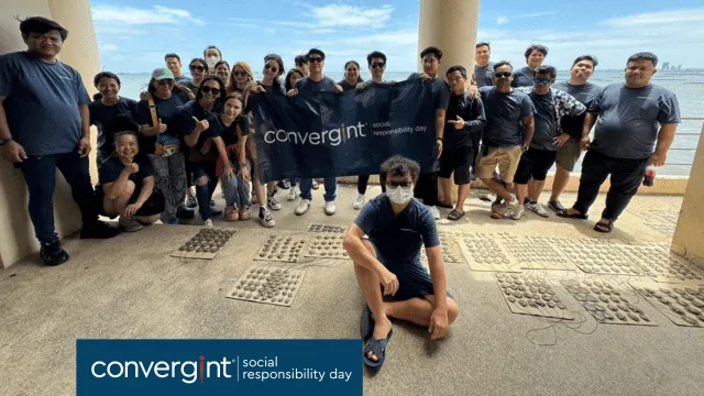 A group of people pose for a photo with a Convergint banner