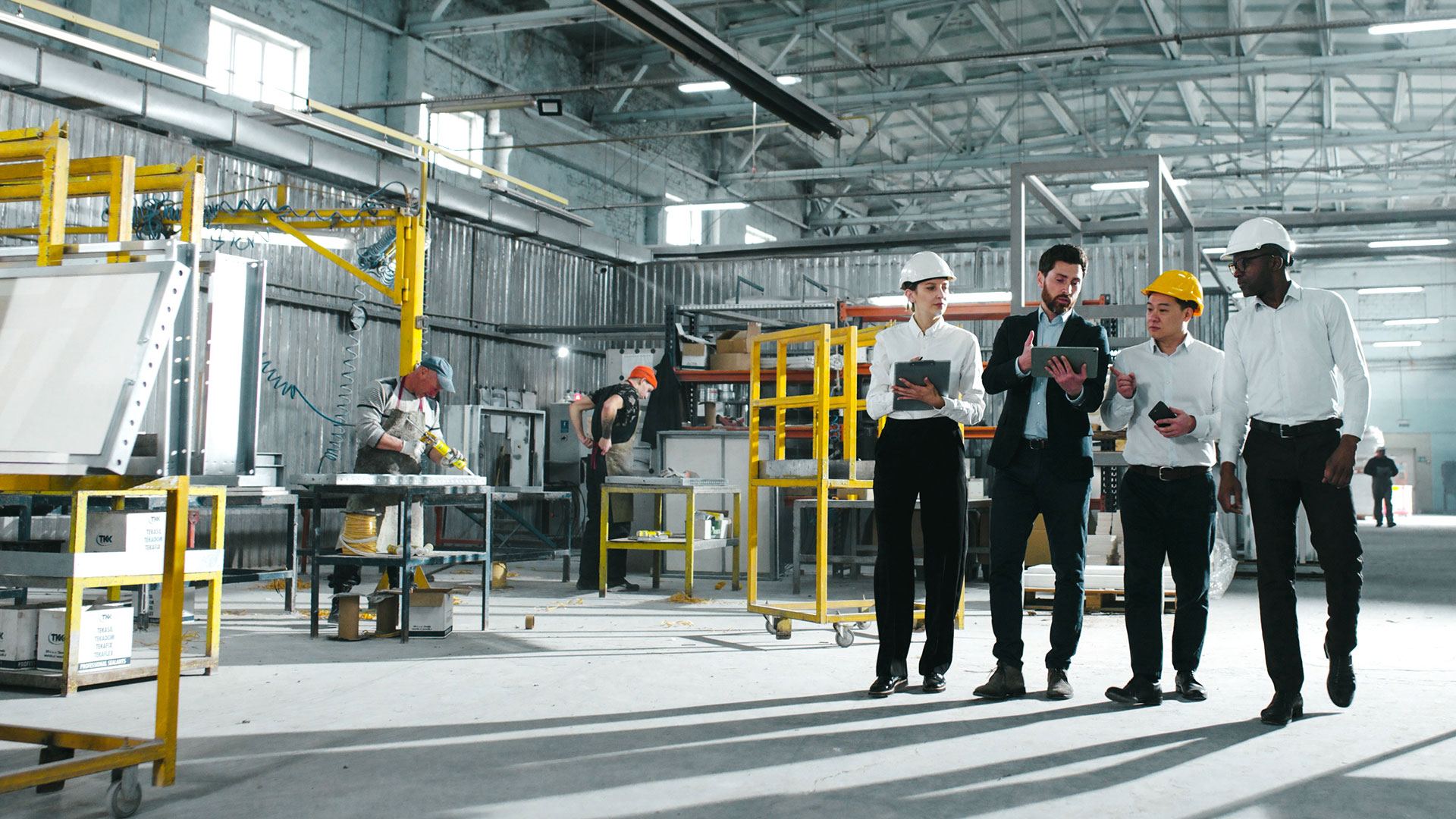Four workers looking over plans on a factory floor