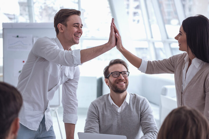 Business people at the conference. Colleagues are giving high five and smiling