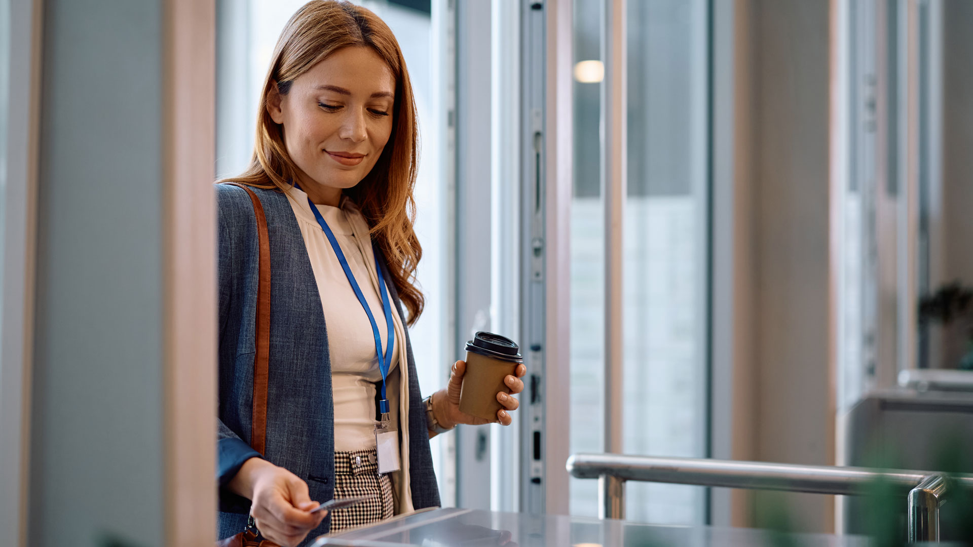 Smiling businesswoman using smart card while coming to work in the office.