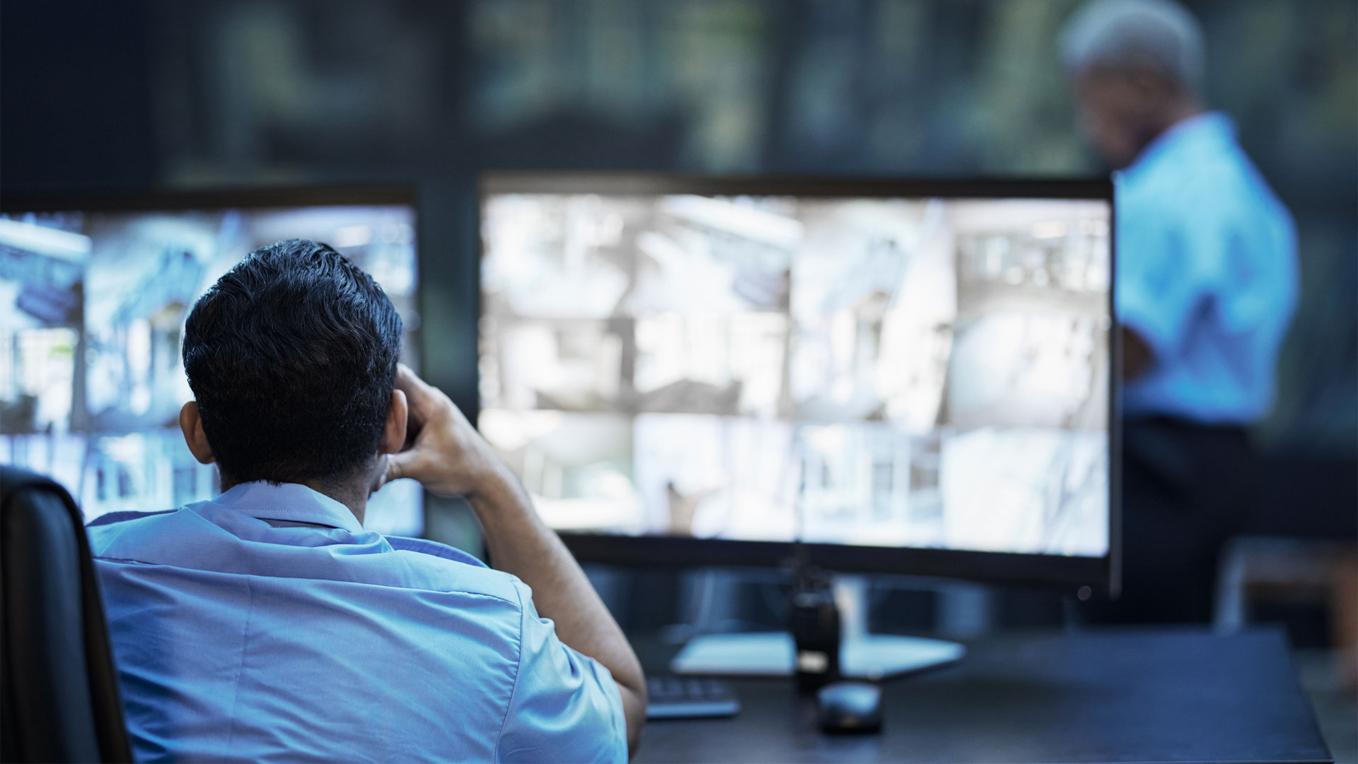 Security guard in control room, man checking cctv screen in surveillance office for building safety