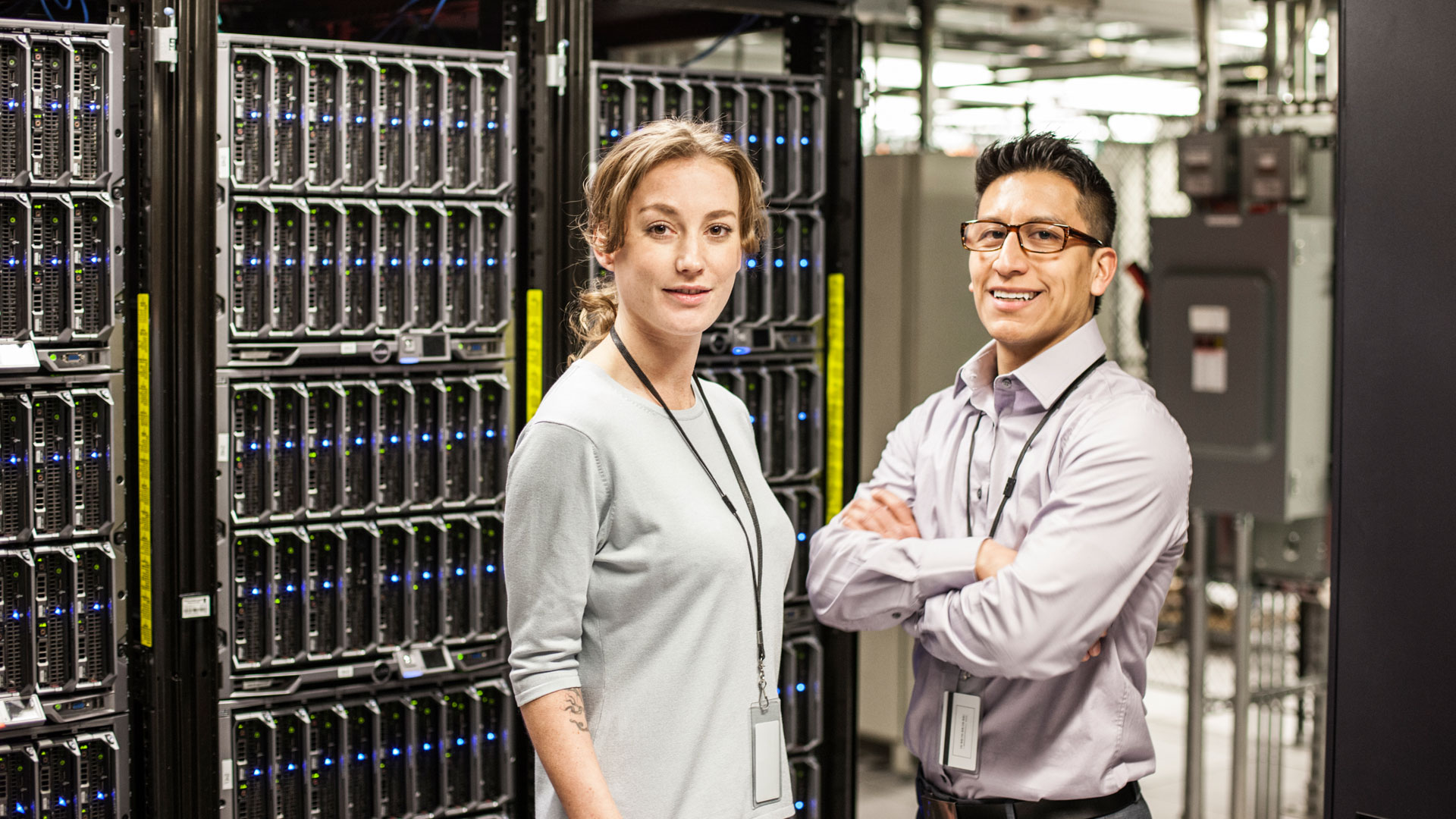 Caucasian man and woman technicians in a large computer server farm.