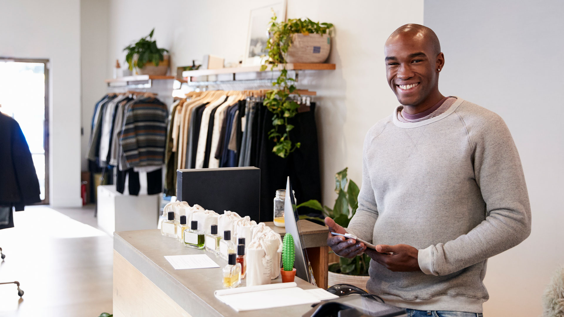 Male assistant smiling behind the counter in clothing store.