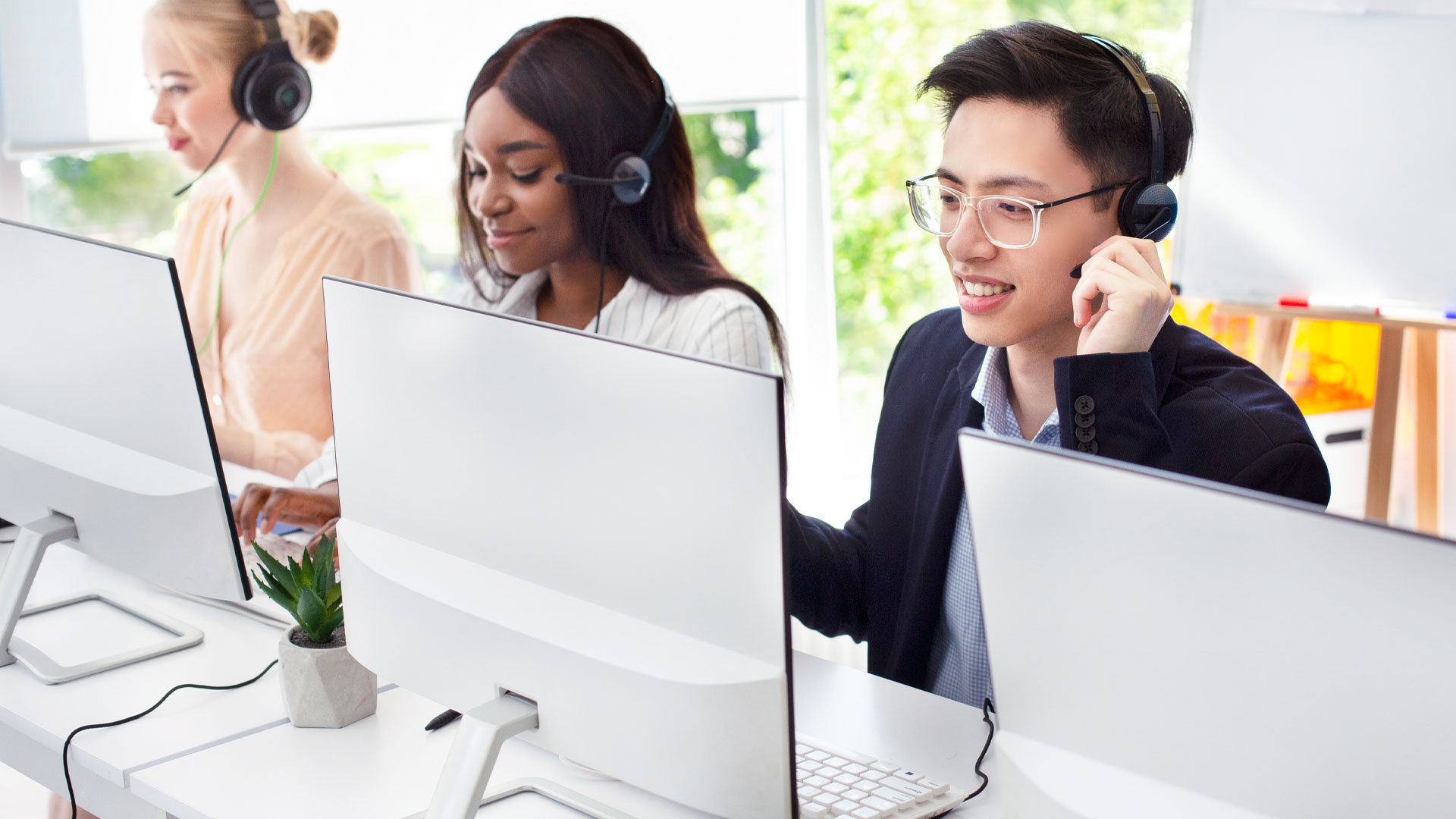 Team of helpline operators with headsets consulting clients at call center