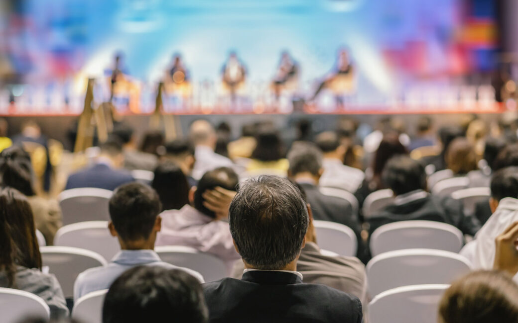 Rear view of audience listening to speakers