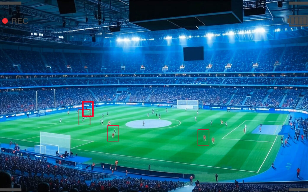 a security camera view of a soccer stadium filled with people with red squares tracking players across the field